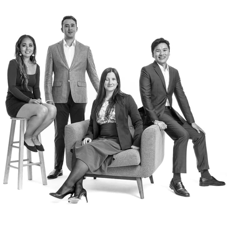 Four students in business attire pose together for a photo in a studio.