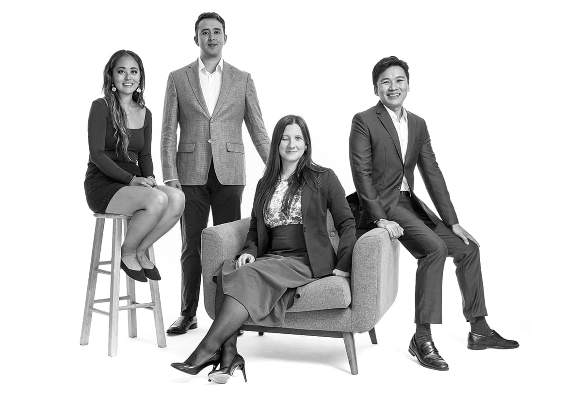 Four students in business attire pose together for a photo in a studio.