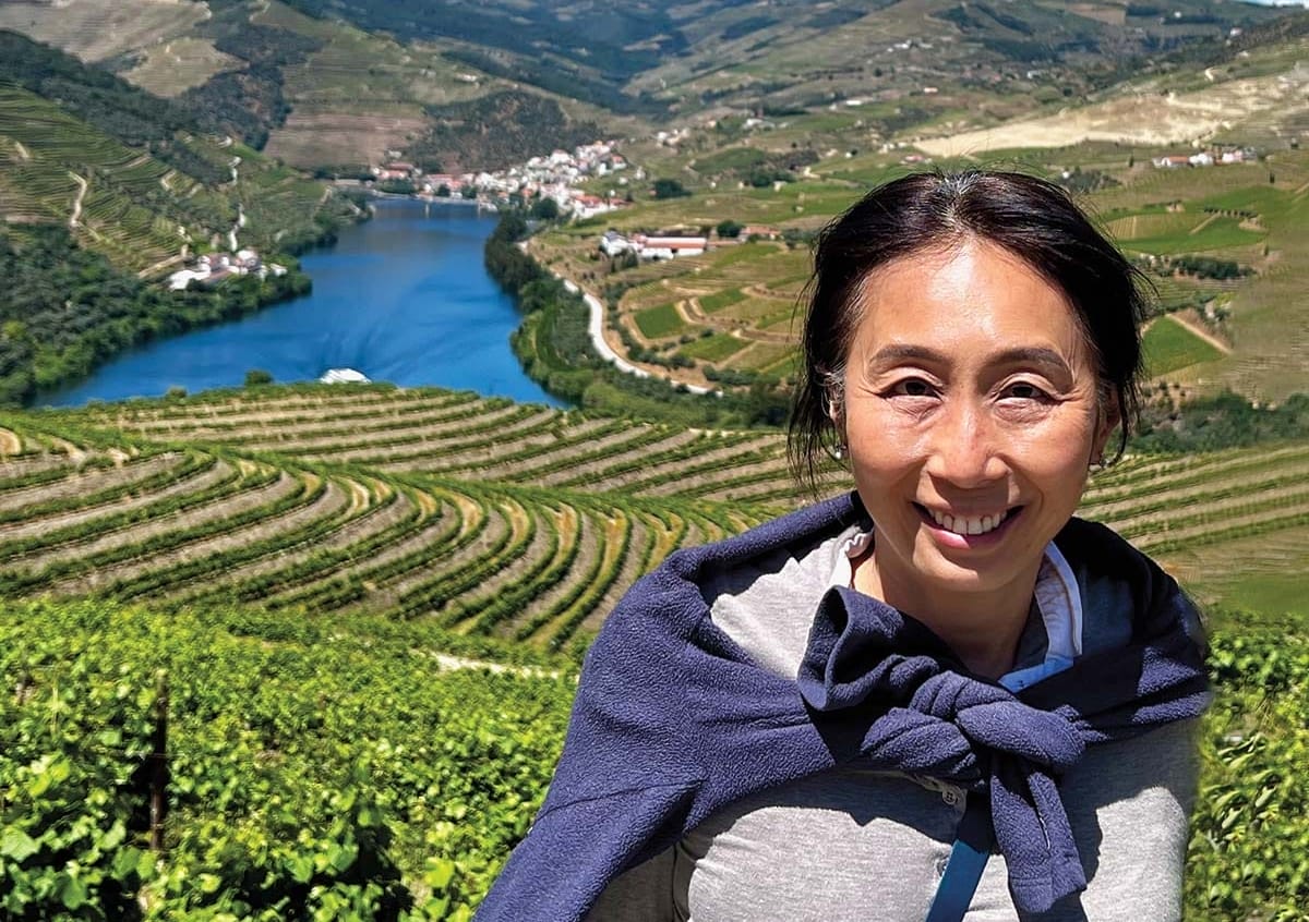 Portrait of a woman in front of a hilly green landscape and waterway.