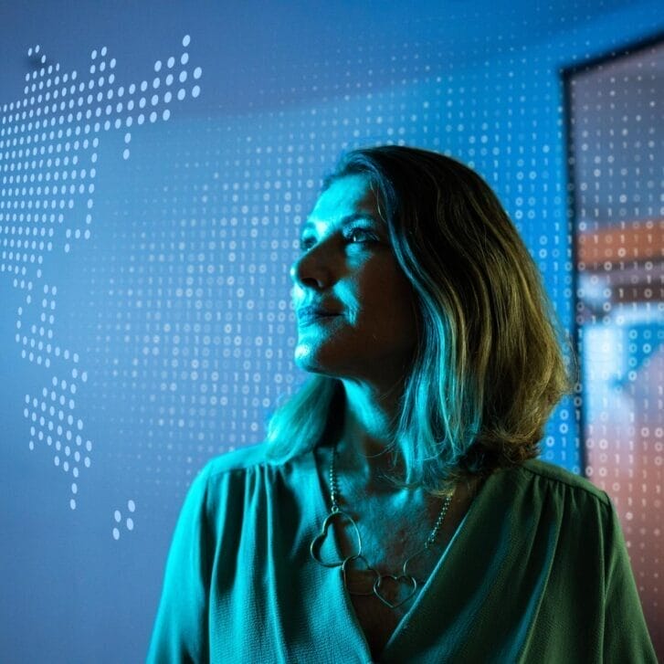 Woman gazing upwards in front of a digitized map of the world