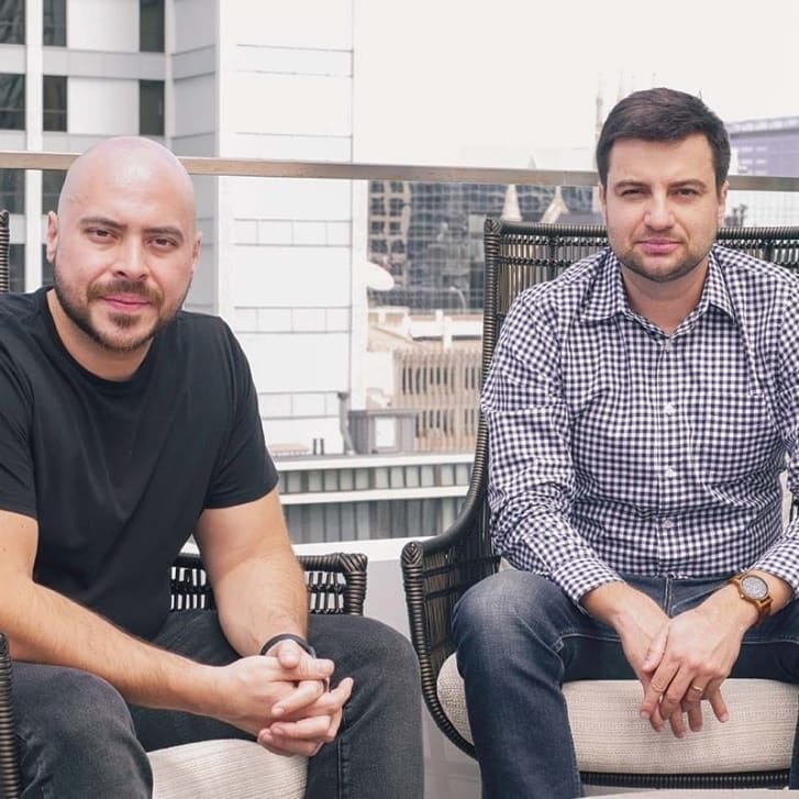 Sigo Seguros founders Nestor Hugo Solari and Julio Erdos seated in chairs on a rooftop.