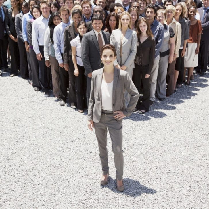 Portrait of confident businesswoman with team of business people in background.