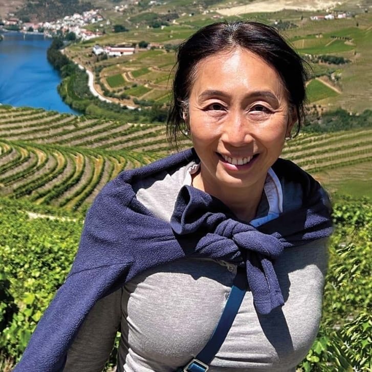 Portrait of a woman in front of a hilly green landscape and waterway.