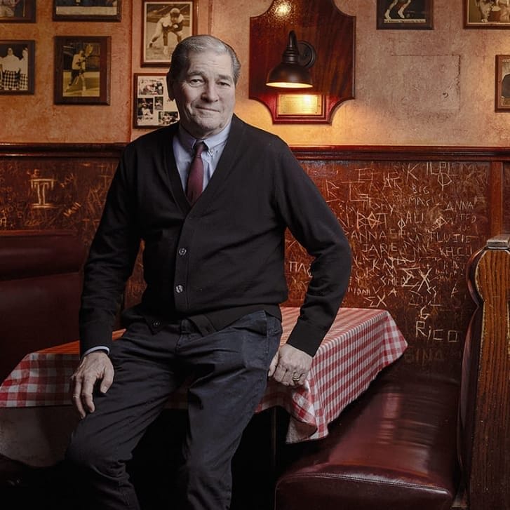 Paul Ryan and son Paul Ryan III sitting on a tabletop and chair, respectively, in their bar Smokey Joe's.