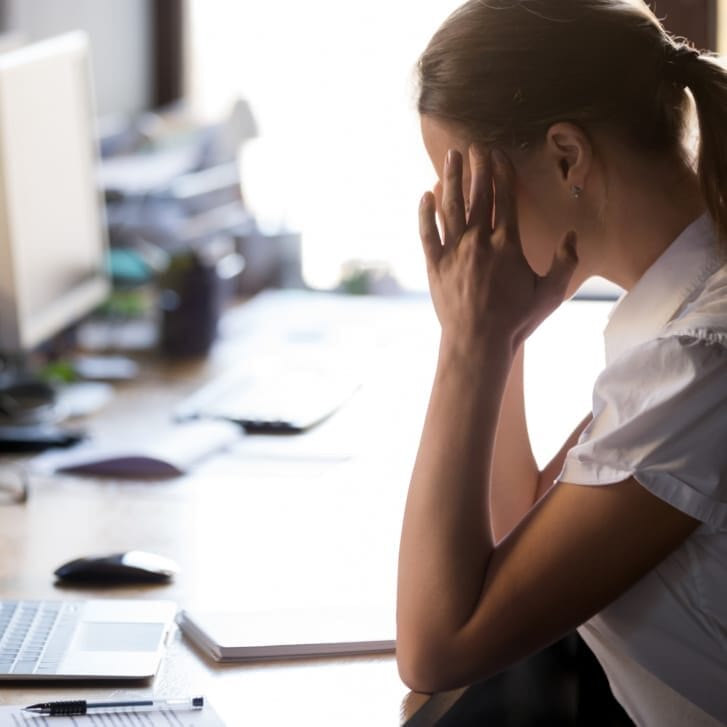 Woman with hands on forehead staring at computer