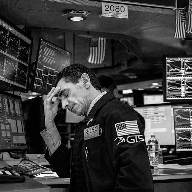 A stock-market trader rubbing his forehead in frustration.