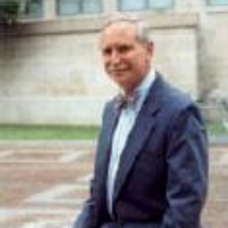 A man wearing a suit is sitting outside.