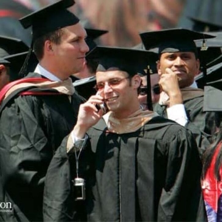 Wharton students gathered at graduation with a few talking on the phone.