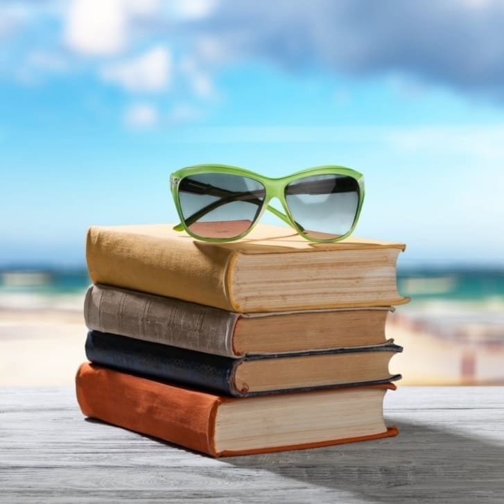 Books and sunglasses on beach background