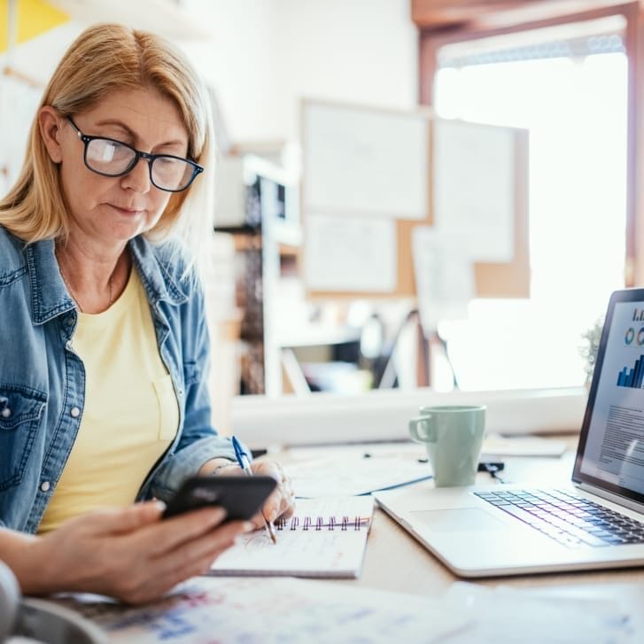 Woman using phone and laptop to work