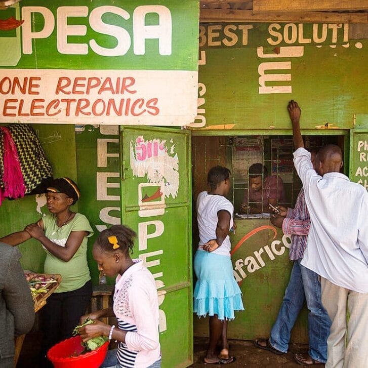 People stand outside a green M-Pesa stand.