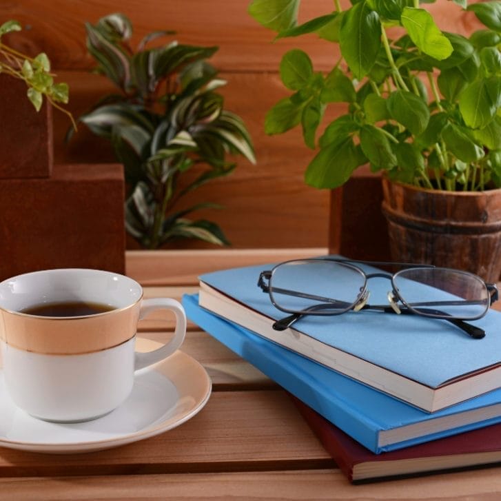 A cup of coffee next to a stack of books on a table.