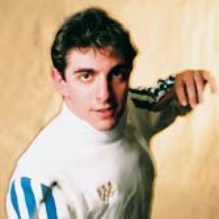 A man stands in a fencing uniform.