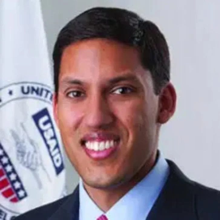 Smiling man poses in a suit and red tie.