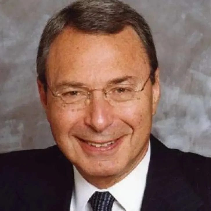 Man in glasses poses in a suit and tie.