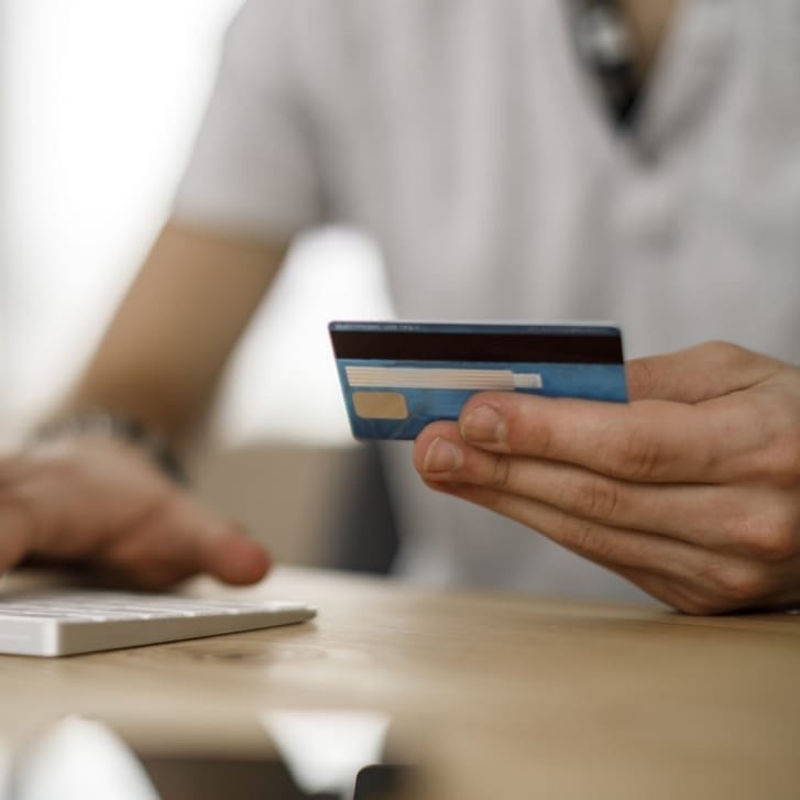 Person in front of a computer holding a credit card.