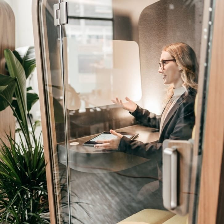 A woman speaking in an enclosed office pod.