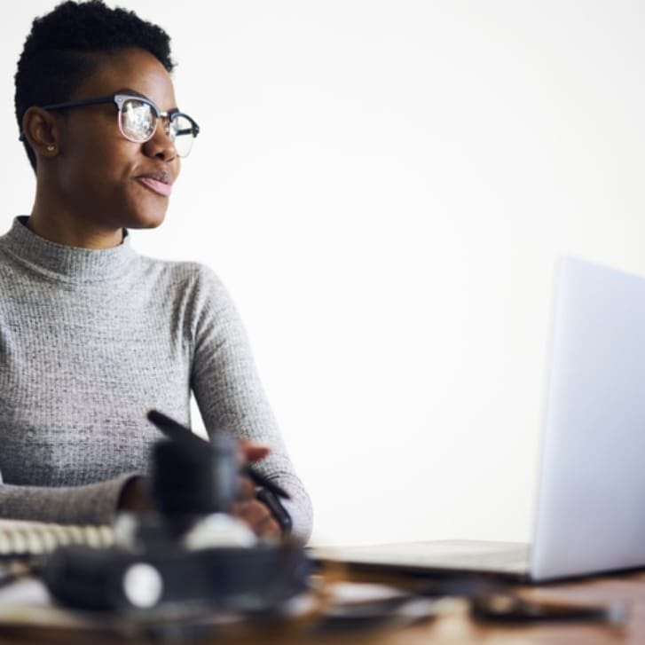 Woman at a computer holding a pen.