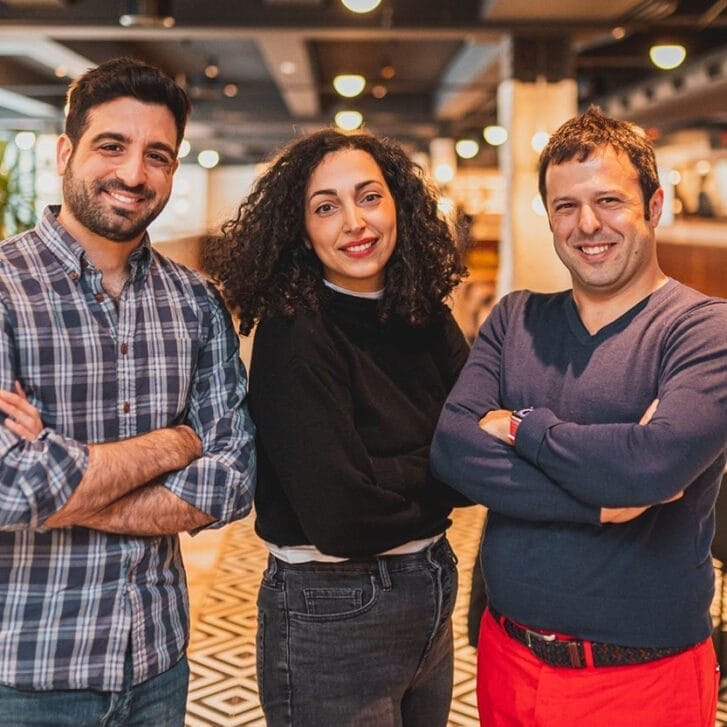 Stepful's three founders pose together for a photo in a lounge area.