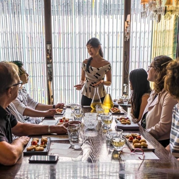 Ashley Lim serving tea to people seated around a table.