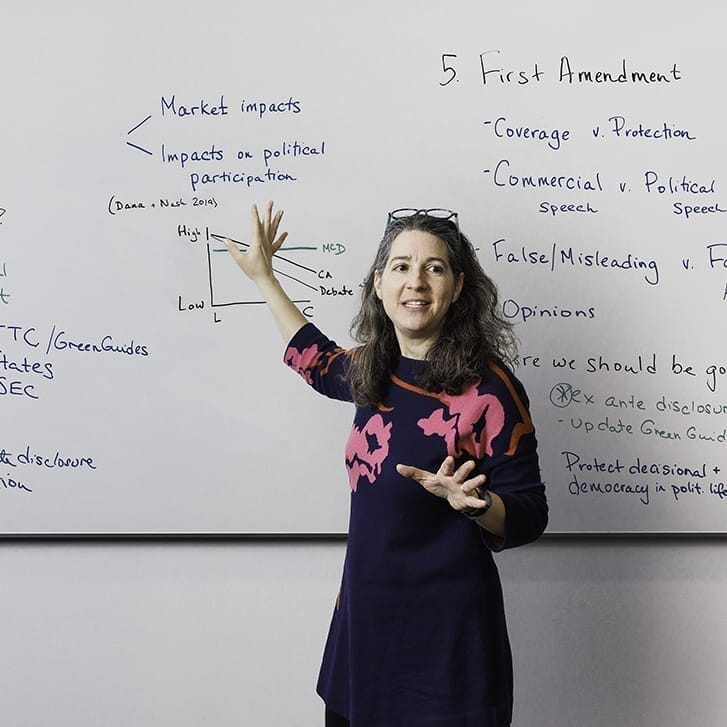 Professor Sarah Light stands in front of whiteboard, explaining the material on it.