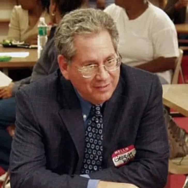 Man wearing glasses and a suit seated at a table.