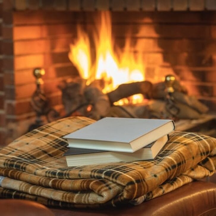 Stack of books in front of a fireplace.