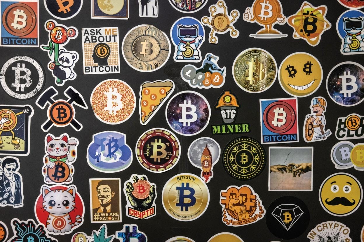 Bitcoin-themed stickers on a black wall.