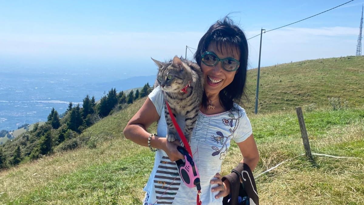 A woman poses for a photo with a cat on her shoulder.