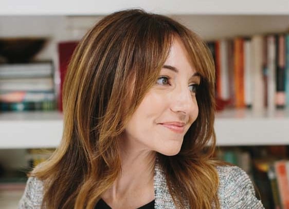 A woman wearing a cardigan looks to the right.