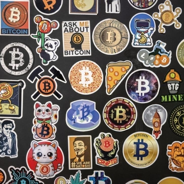 Bitcoin-themed stickers on a black wall.
