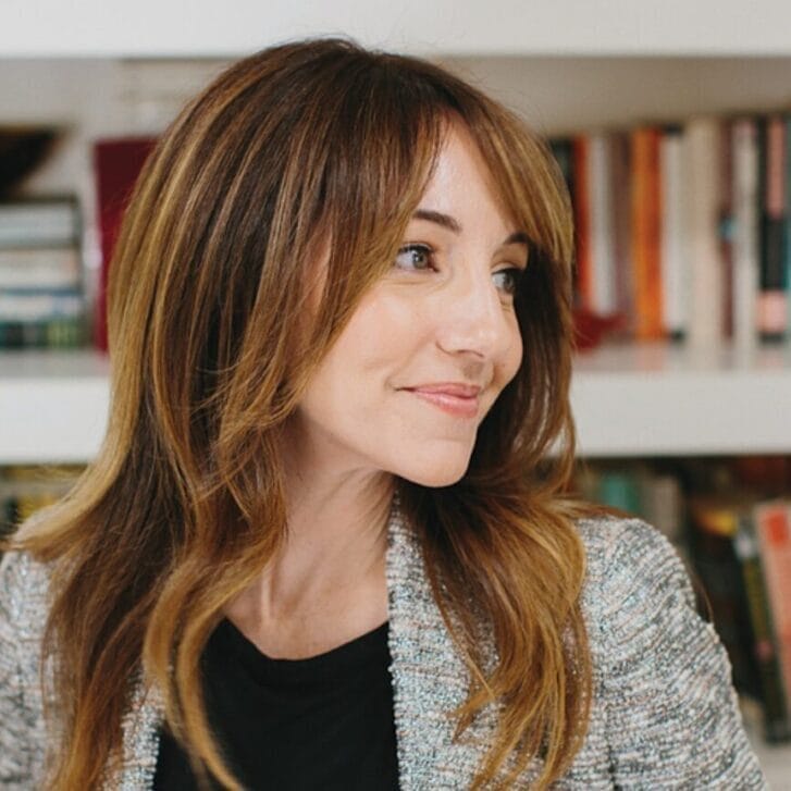 A woman with red hair looks to the side.