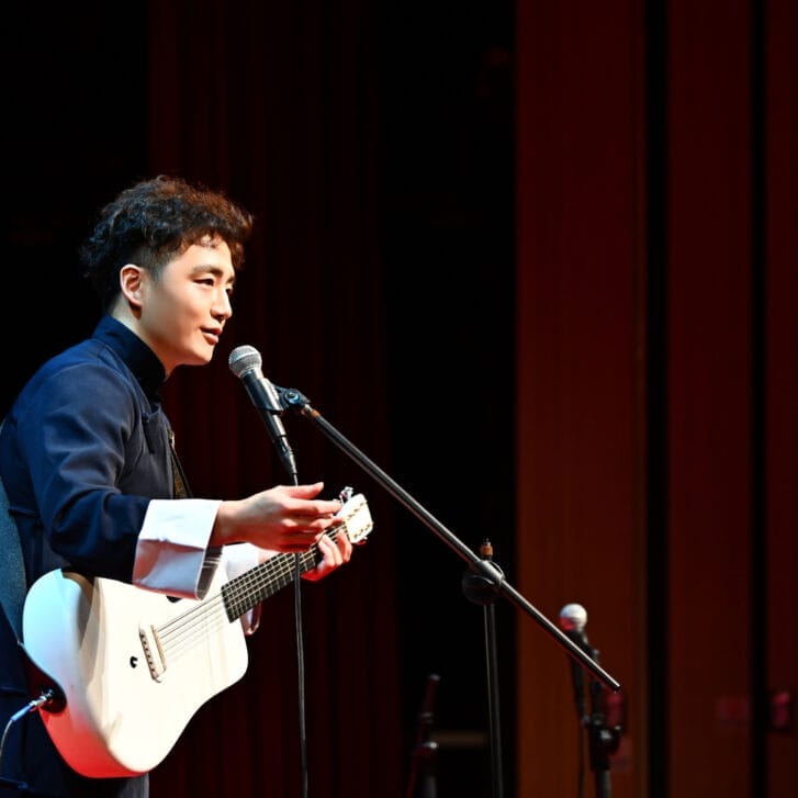 Man playing a guitar in front of a microphone