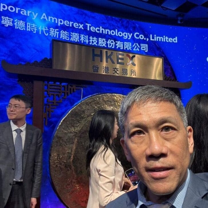 Man standing in front of the Hong Kong Stock Exchange gong