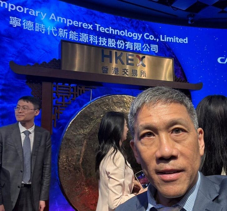 Man standing in front of the Hong Kong Stock Exchange gong