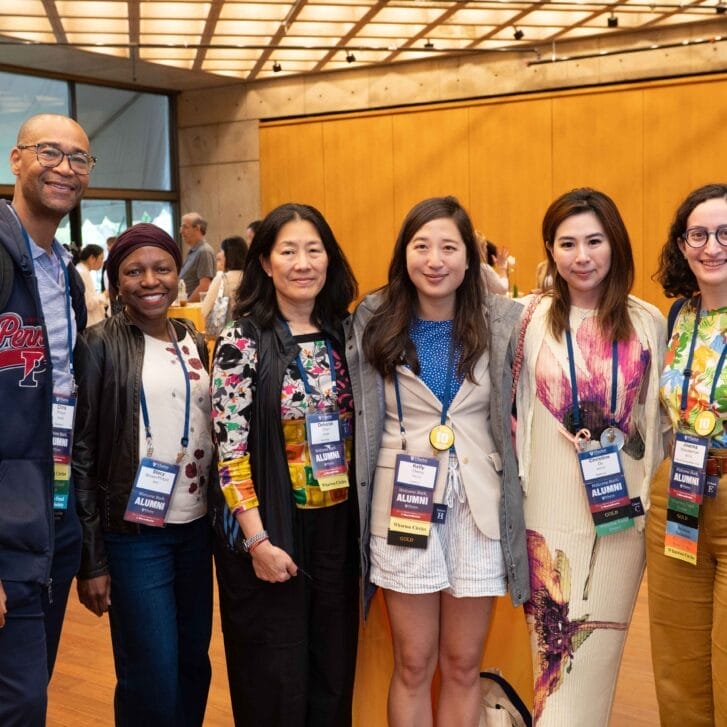 A group of six people wearing name tags stand together smiling