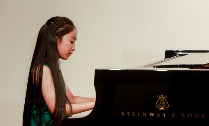 A performer sits down in front of a Steinway piano.