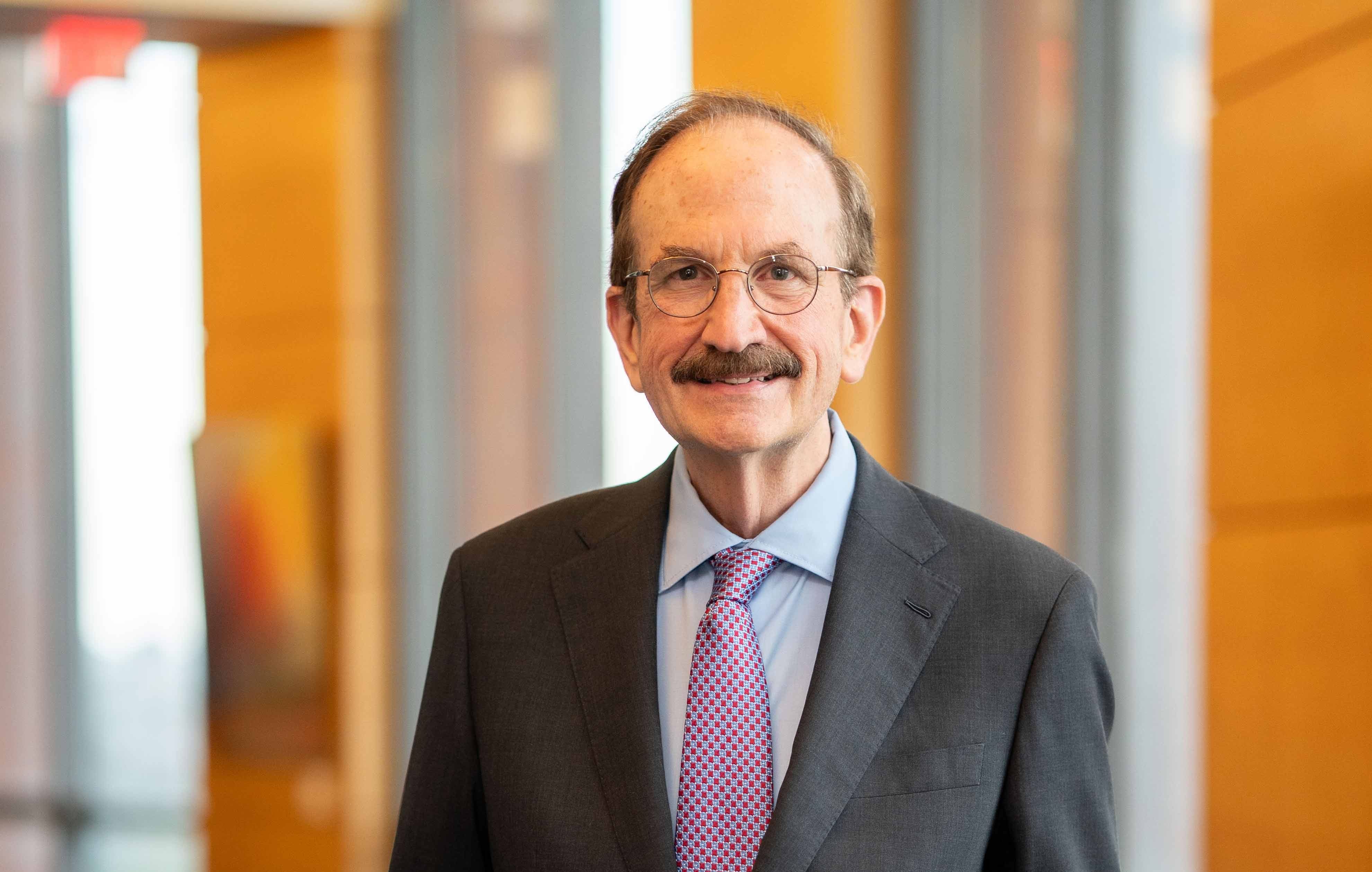 Dr. Bruce Jacobs standing in Huntsman Hall, wearing a suit and tie