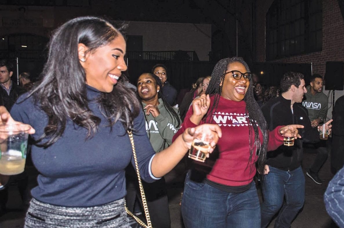 People lined up on a dance floor with cups in hand.
