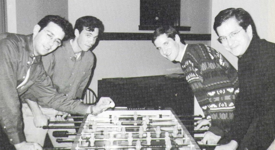 Black-and-white photo of four men playing foosball.