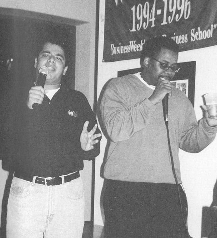 Black-and-white photo of two men singing karaoke.