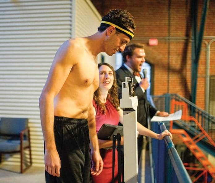 A shirtless man steps on a scale.