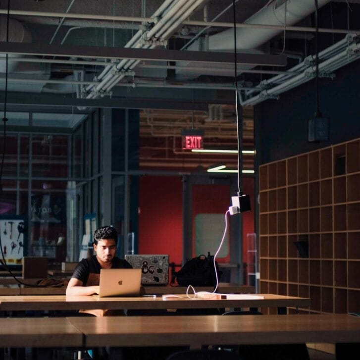 Young man sitting in front of a laptop in an empty laboratory room.
