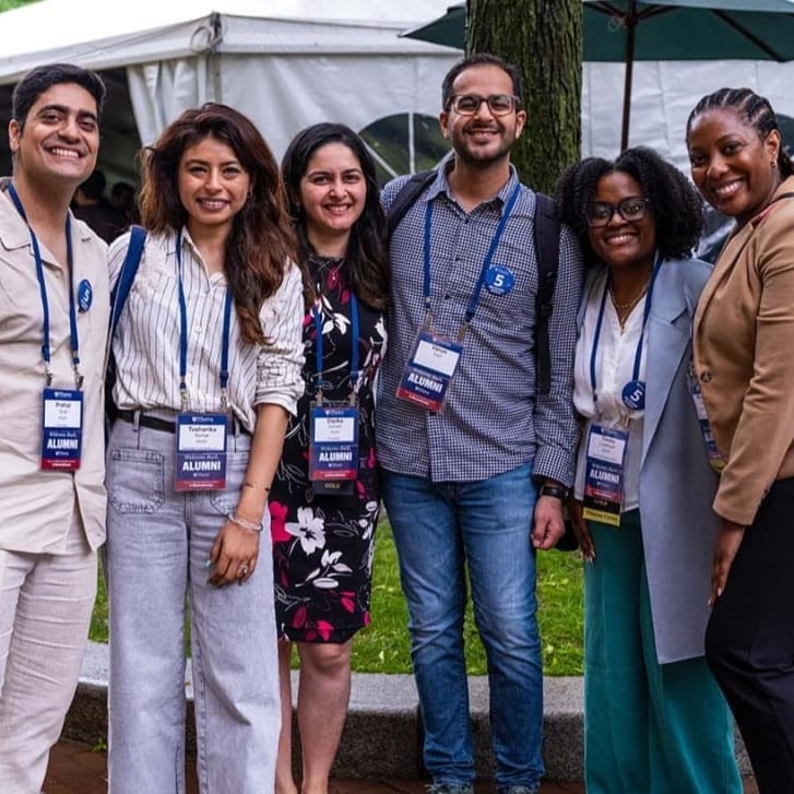 Group of people standing outside near a white tent.