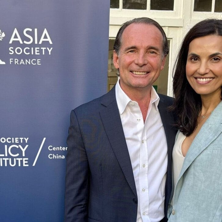 Man and woman pose in front of a banner with an 