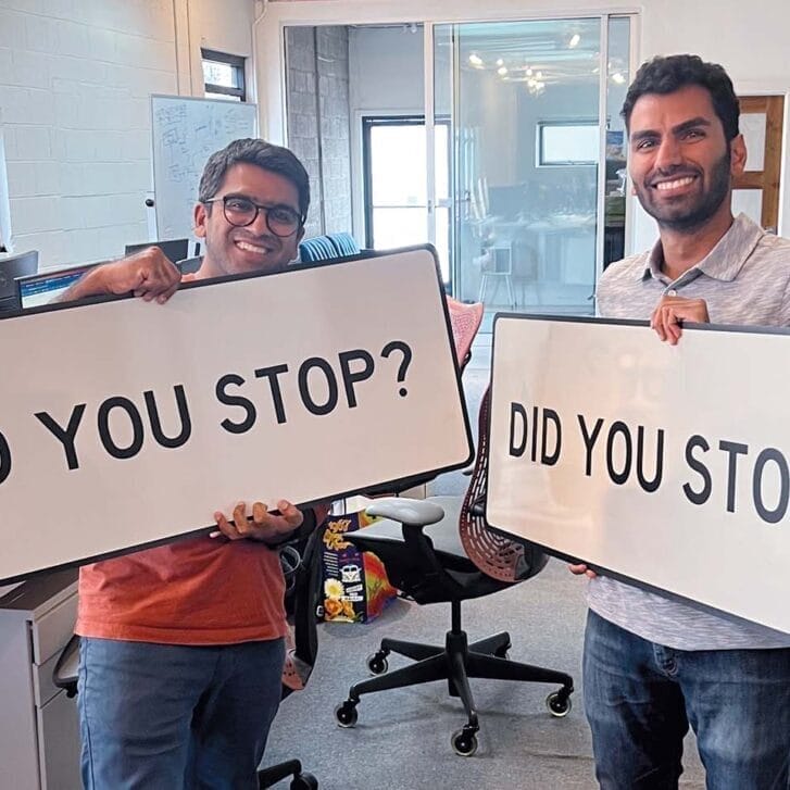 Two men standing next to each other while holding signs that say 