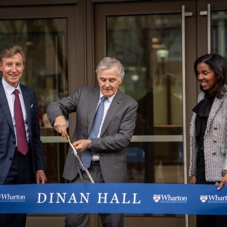 Jamie Dinan W81 cuts a giant ribbon as Dean Erika James and Penn President Larry Jameson stand on either side of him