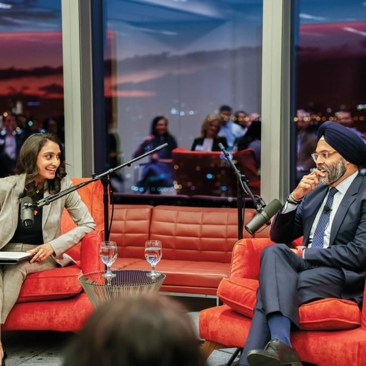 Woman and man sitting near each other talking, with a large floor-to-ceiling window behind them.