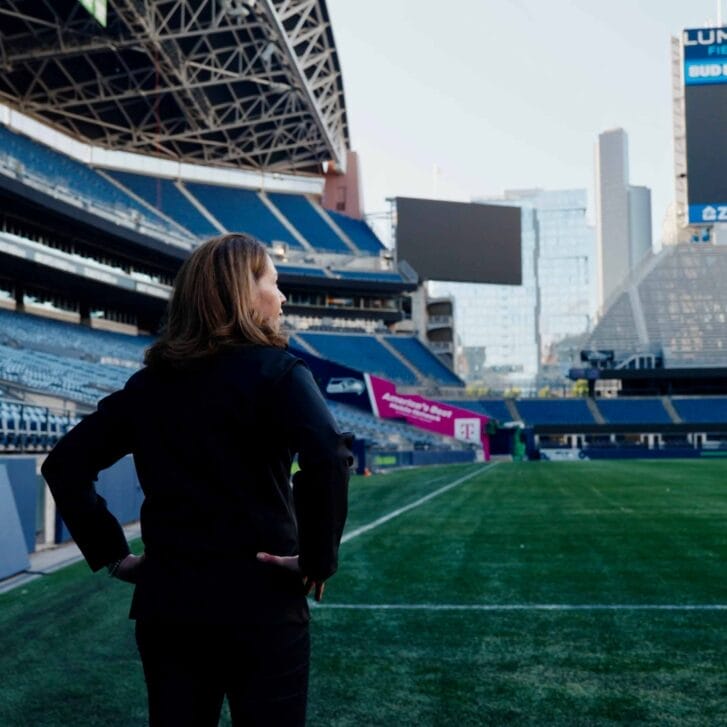 Woman with hands on her hips looking toward an empty football field