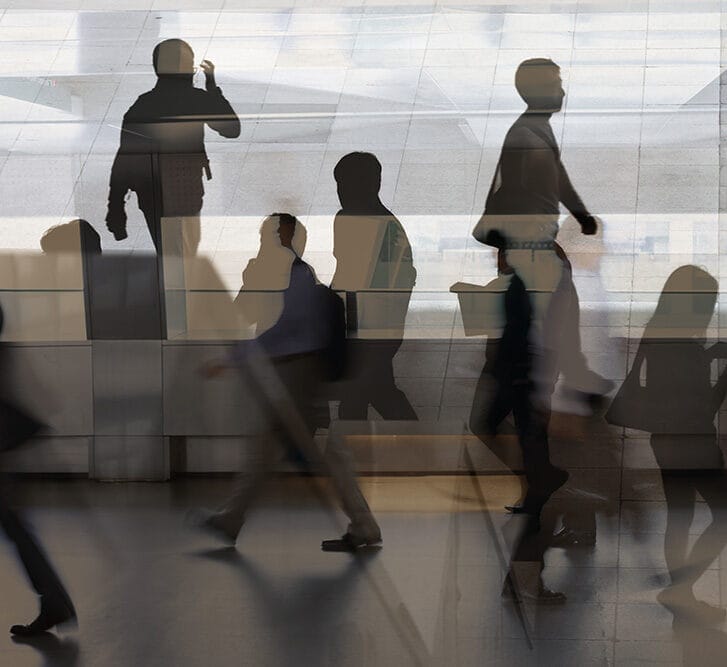 Silhouetted people walk in a hallway.